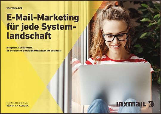 Cover eines Whitepapers von Inxmail mit dem Titel 'E-Mail-Marketing für jede Systemlandschaft - Integriert. Funktioniert. So bereichern E-Mail-Schnittstellen Ihr Business.' Das Bild zeigt eine junge Frau mit Brille, die lächelnd auf ihrem Laptop arbeitet. Sie sitzt in einem gemütlichen Raum mit Pflanzen im Hintergrund. Das Inxmail-Logo befindet sich unten rechts im Bild.